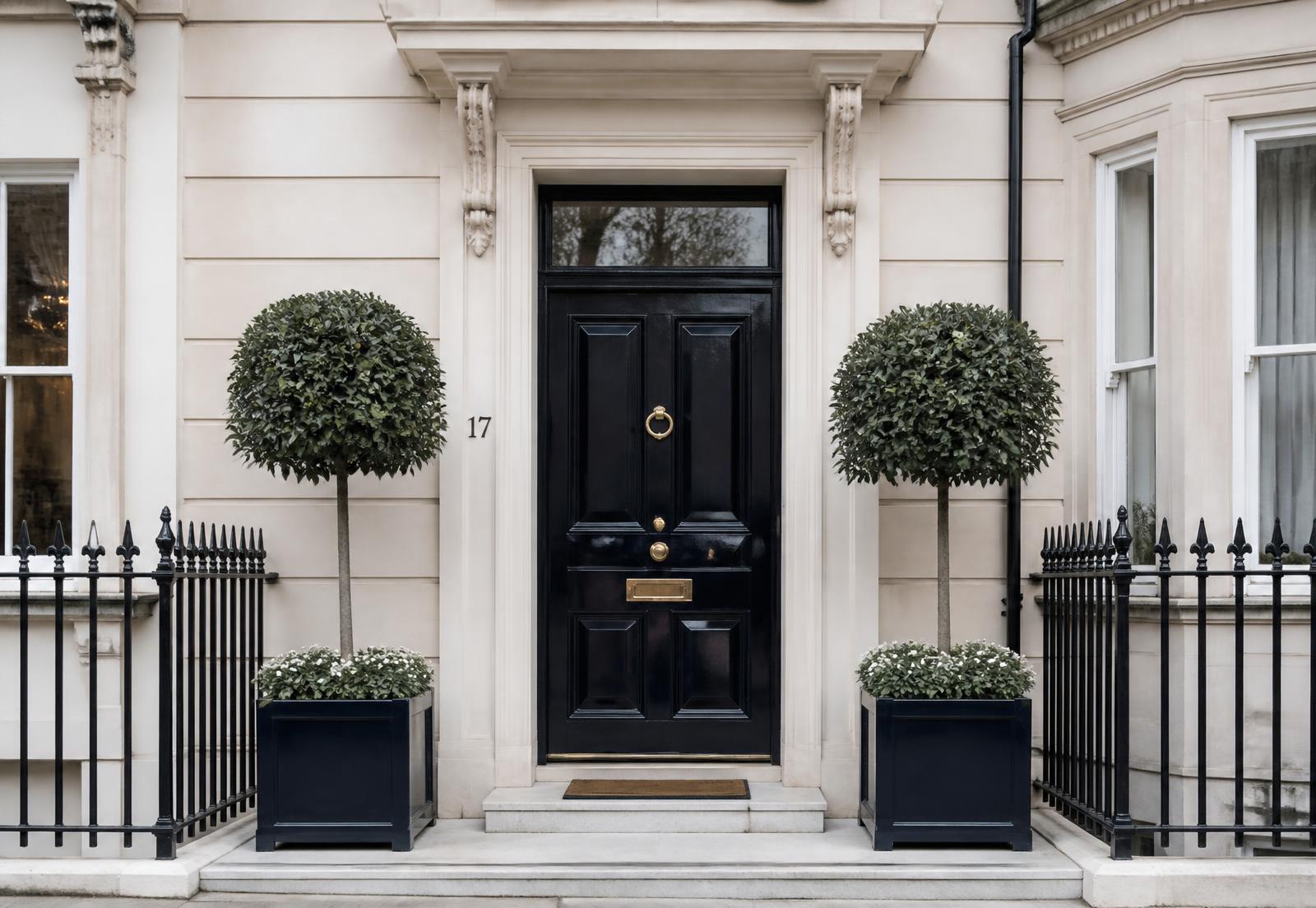 Elegant townhouse entrance with clipped bay trees either side of the front door
